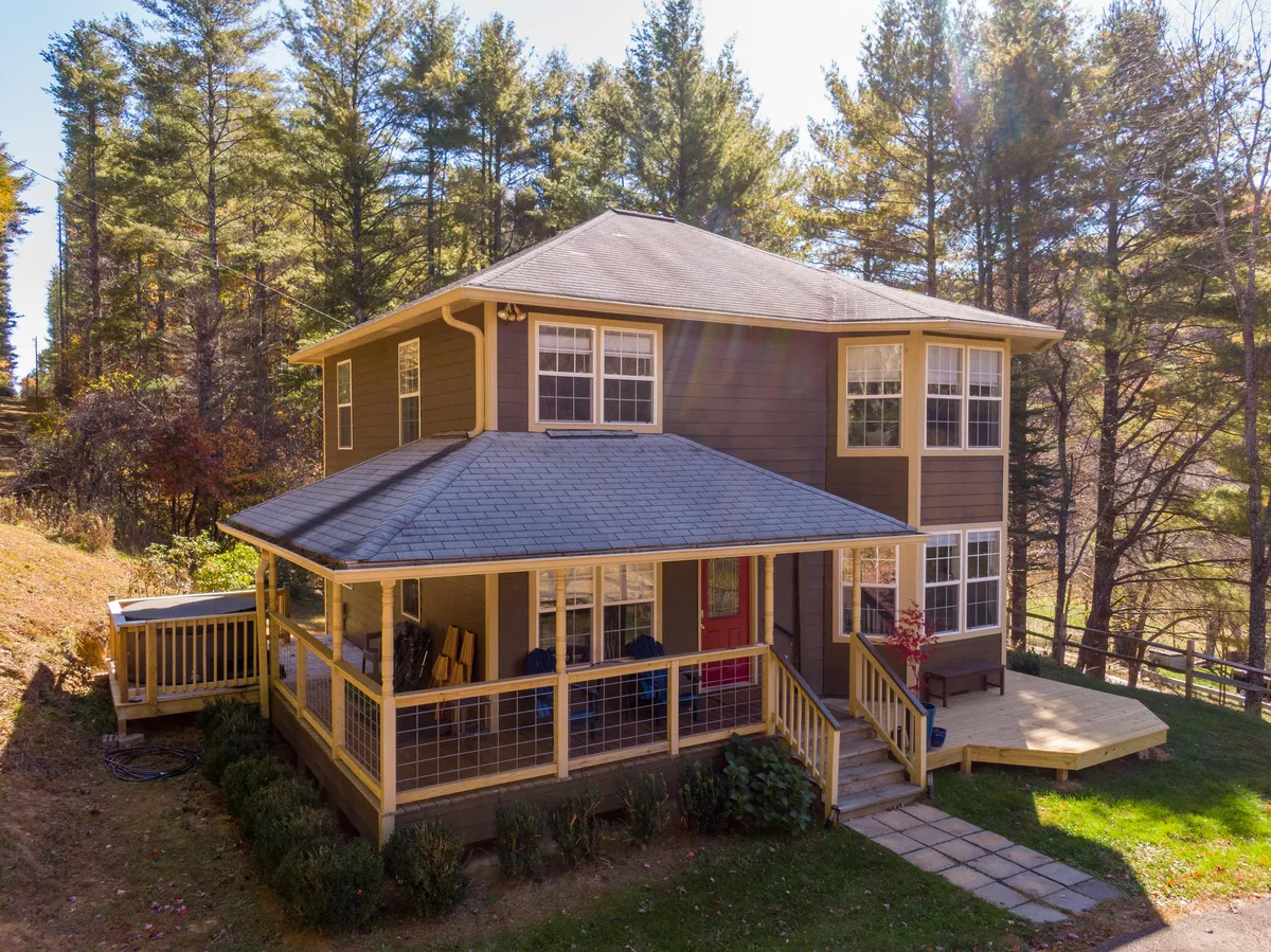 This image captures the front porch of the property surrounded by trees, with a view of the exterior walls. The welcoming porch hints at relaxing outdoor moments and the natural setting that defines the property's year-round appeal. The scene suggests opportunities for stargazing, watching sunsets, and easy access to nature trails.